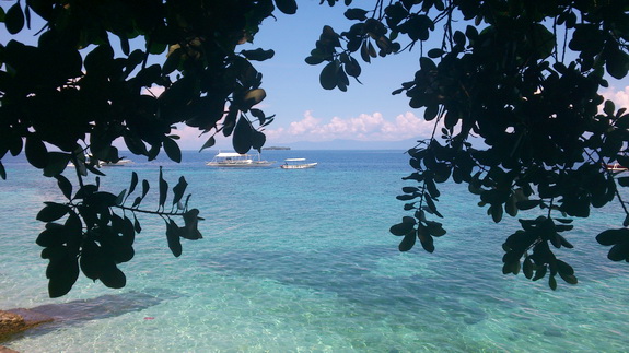 view over the reef of Moalboal, with some outrigger dive boats and Pescador Island in the background